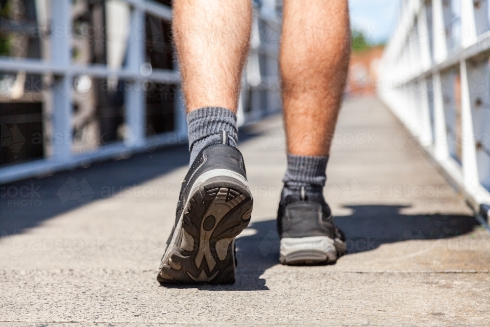 Close up of joggers shoes walking over bridge - Australian Stock Image