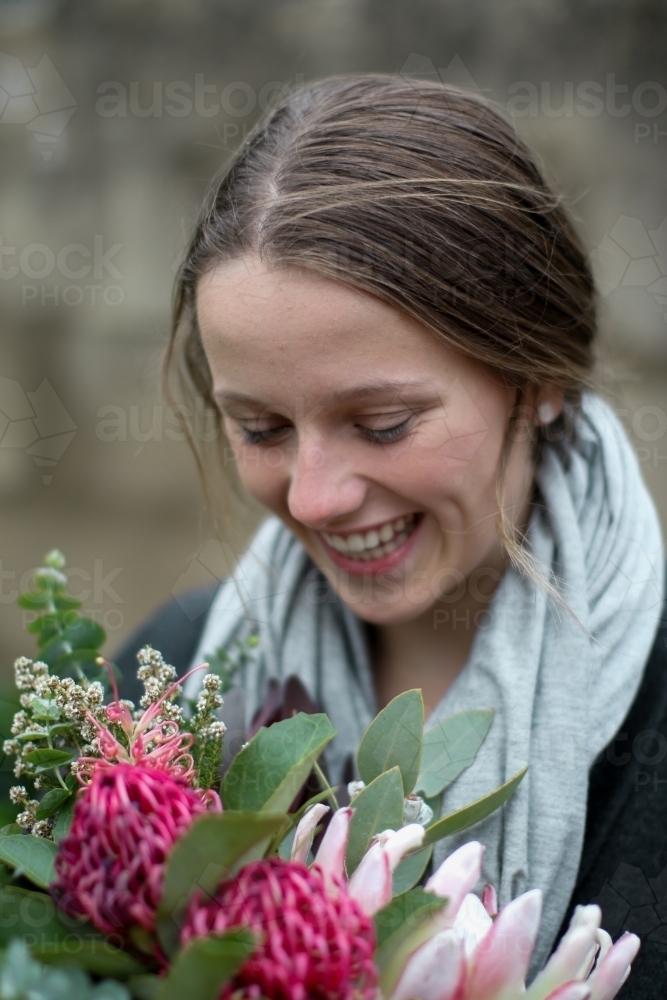 Close up of laughing girl holding a bouquet of native flowers - Australian Stock Image
