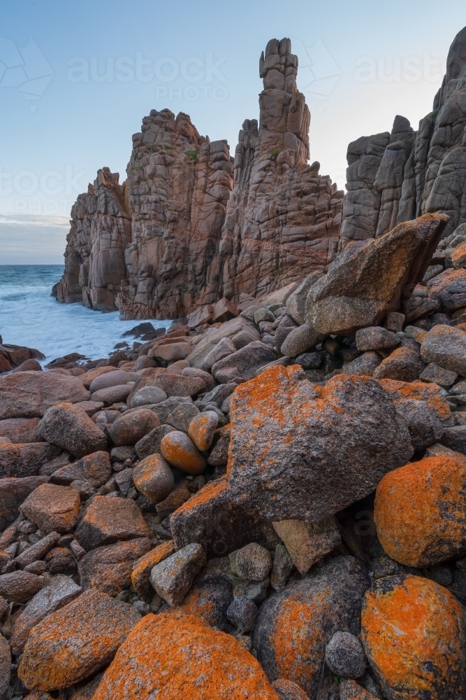 Image of Close up of lichen covered boulders below tall rock formations ...
