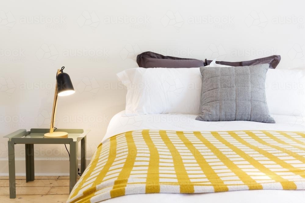 Close up of luxury bed and bedside table with lamp in designer home - Australian Stock Image