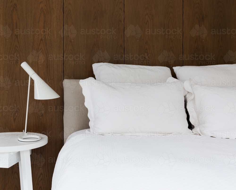 Close up of luxury white linen in bedroom with walnut lining boards on the wall behind - Australian Stock Image