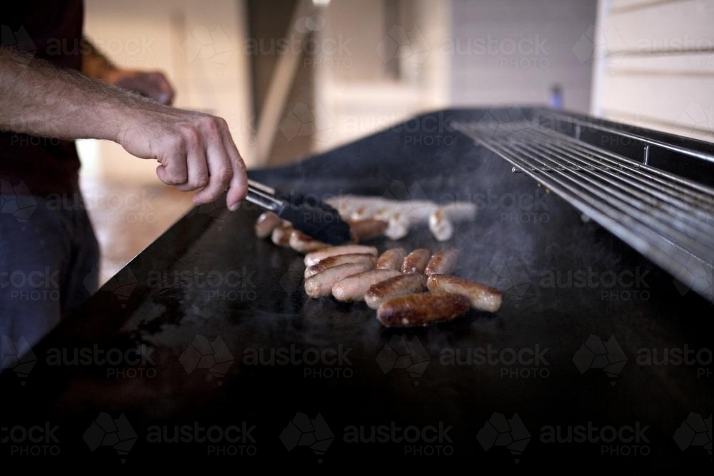Close up of man cooking sausages on a barbeque - Australian Stock Image