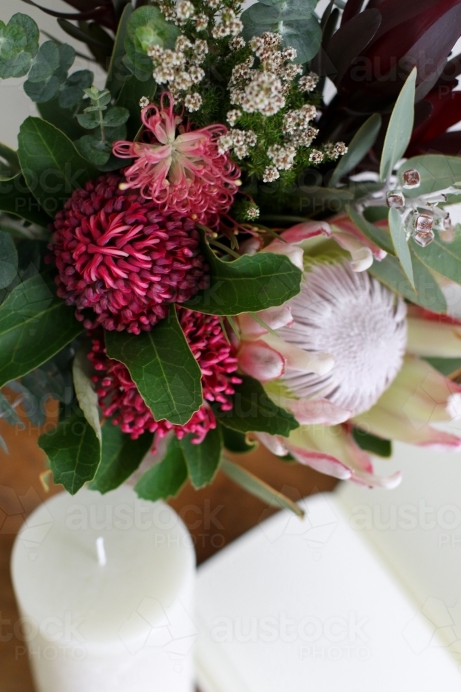 Close up of native floral arrangement with candle and notebook in background - Australian Stock Image
