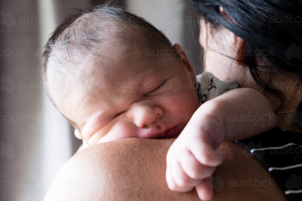 Close up of Newborn baby sleeping on mothers shoulder - Australian Stock Image