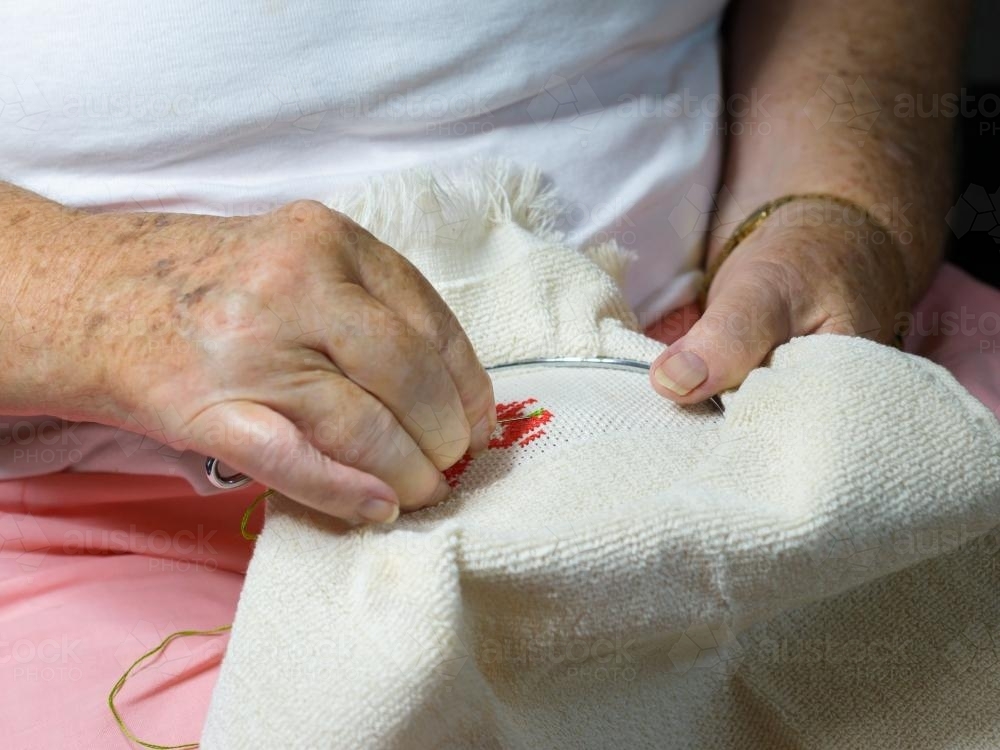 Close up of old woman's hands doing embroidery - Australian Stock Image