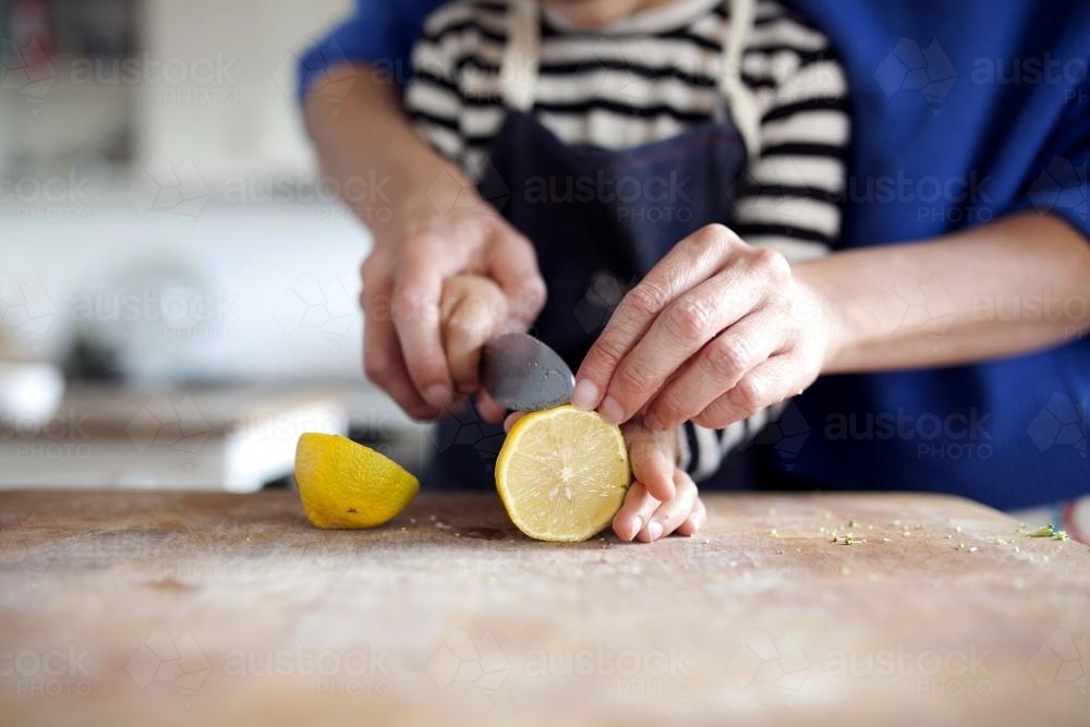 Close up of parent helping child cut lemon - Australian Stock Image