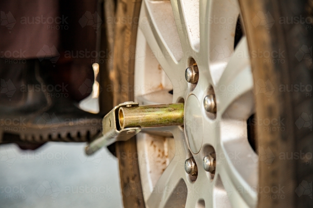 Close up of person changing a flat tyre unscrewing wheel nuts - Australian Stock Image