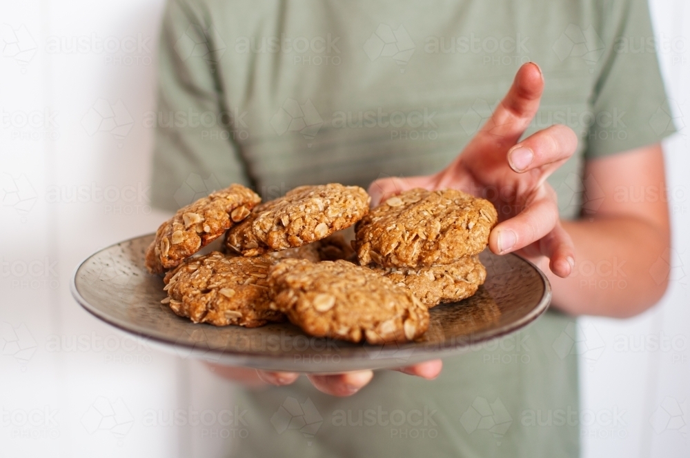 Close up of plate of cookies held by child - Australian Stock Image