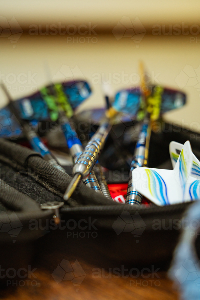 Close-up of professional steel tip darts in black zippered case. - Australian Stock Image