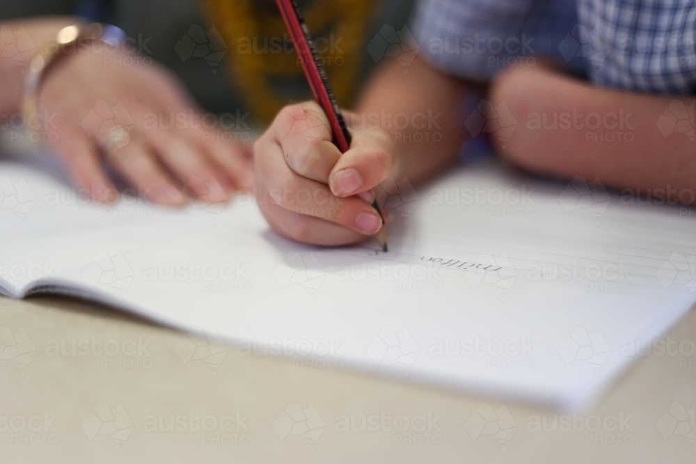Image of Close up of school girl's hand writing in a book - Austockphoto
