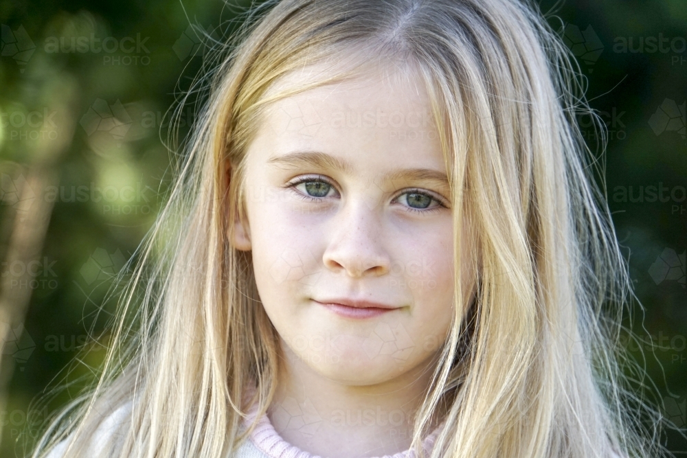 Close-up of Six year old girl with blonde hair looking serious - Australian Stock Image