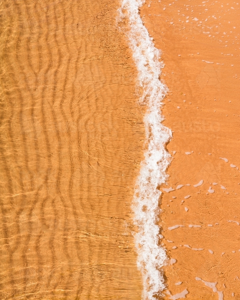 Close up of small wave over rippled sand - Australian Stock Image