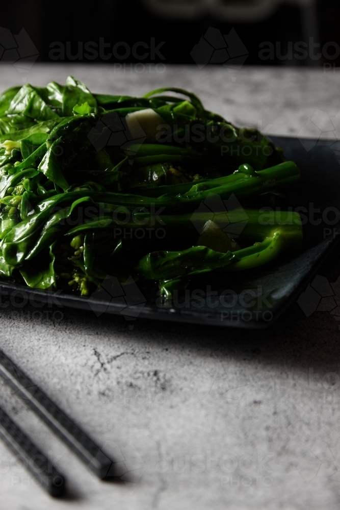 Close up of steamed green vegetables on black plate - Australian Stock Image