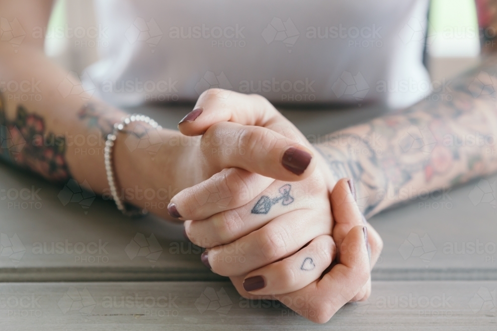 Close up of tattoos on clasped hands of a young woman - Australian Stock Image