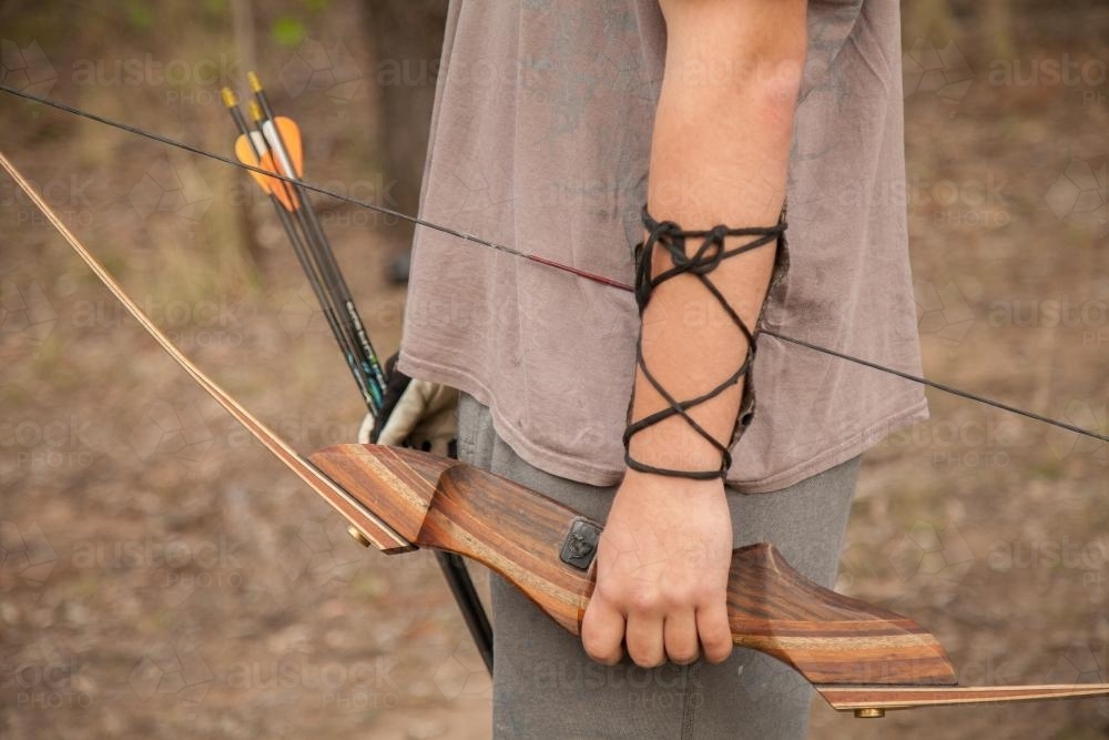 Close up of teen guy holding recurve bow and arrows - Australian Stock Image