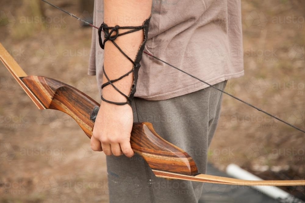Close up of teen guy holding recurve bow and arrows - Australian Stock Image