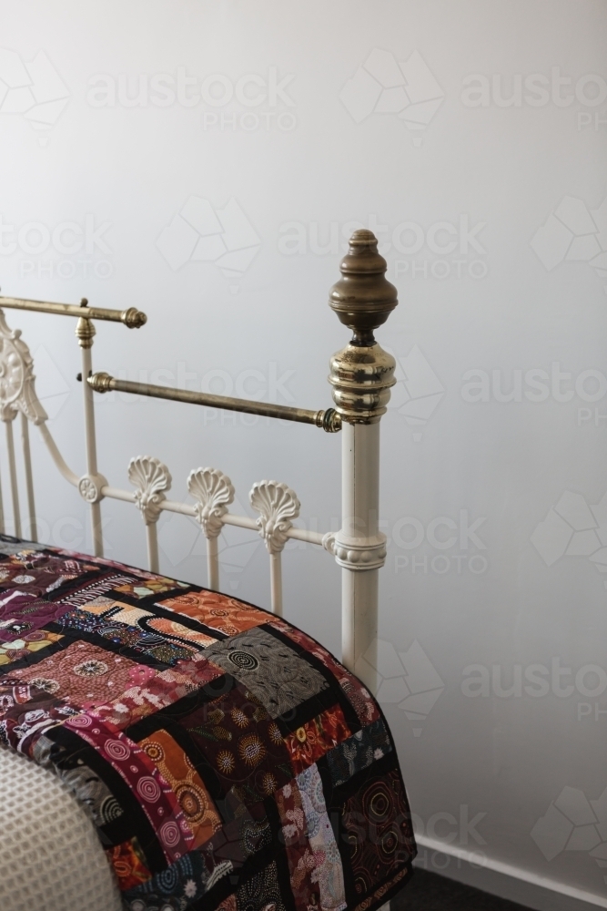 Close up of the corner of a vintage brass bed and quilt - Australian Stock Image