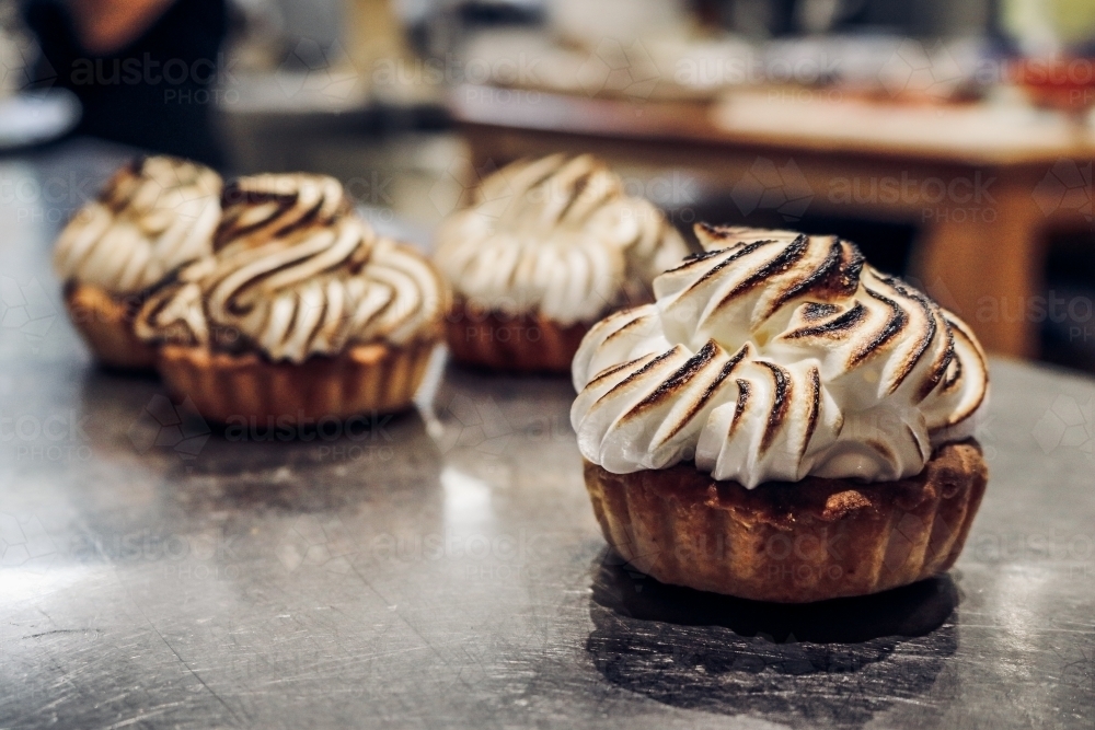Close up of torched meringue tarts on stainless steel counter top - Australian Stock Image