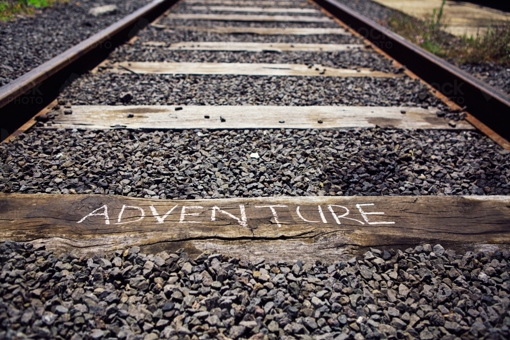 Close up of train track with the word Adventure written on a sleeper - Australian Stock Image