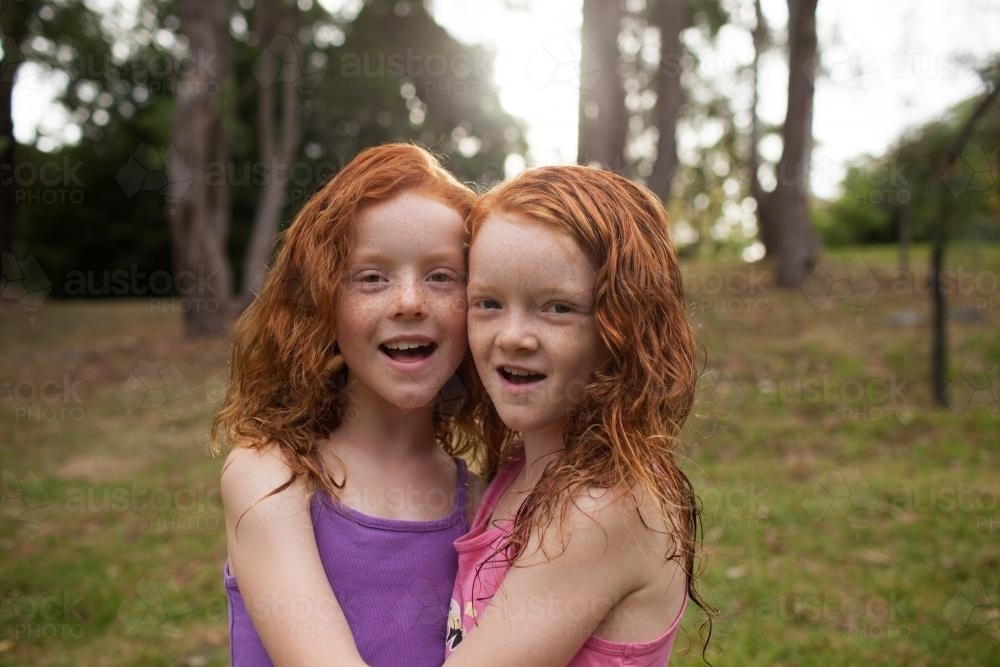 Image of Close up of two girls hugging in a field - Austockphoto