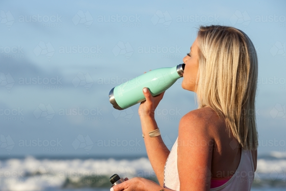 close up of woman drinking from a water bottle after a workout - Australian Stock Image