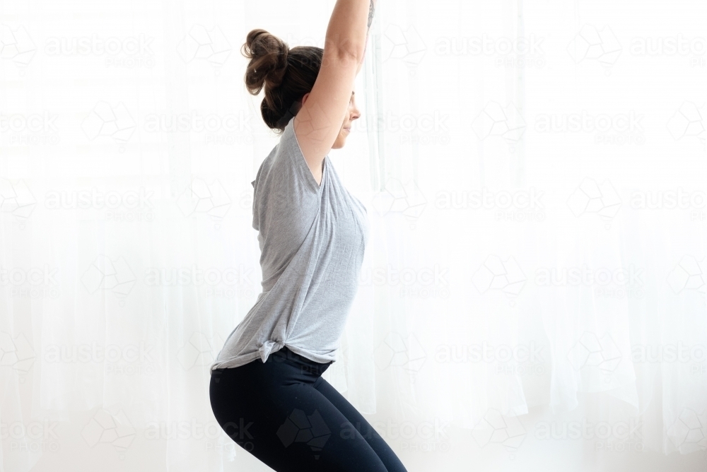 close up of woman in chair pose doing yoga white background - Australian Stock Image