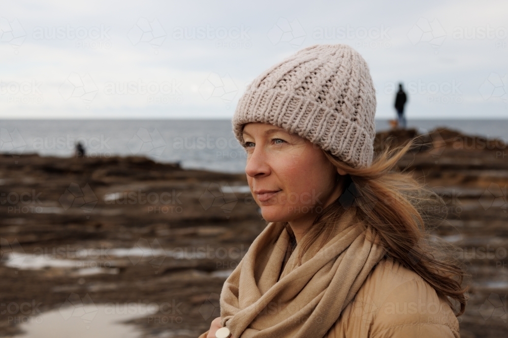 Close-up of woman near rockpools with ocean horizon - Australian Stock Image