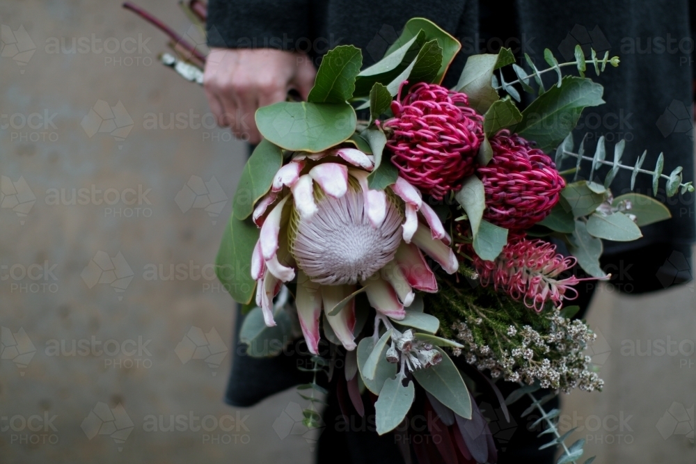 Close up of woman's hand holding a bouquet of native flowers - Australian Stock Image