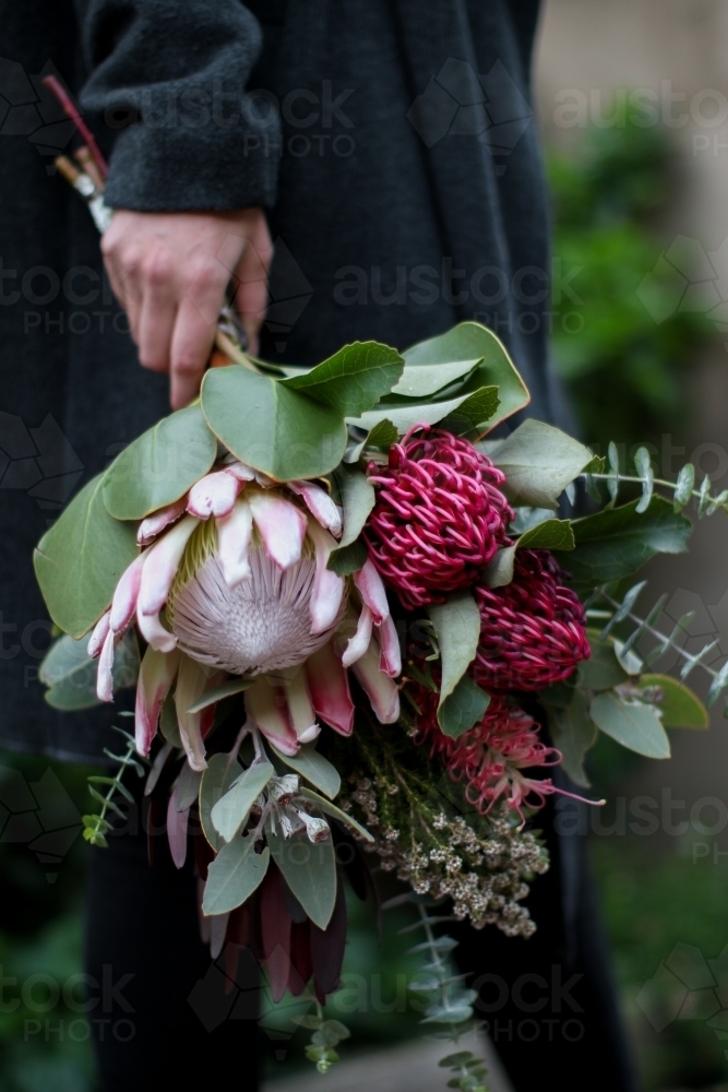 Close up of woman's hand holding a bouquet of native flowers - Australian Stock Image