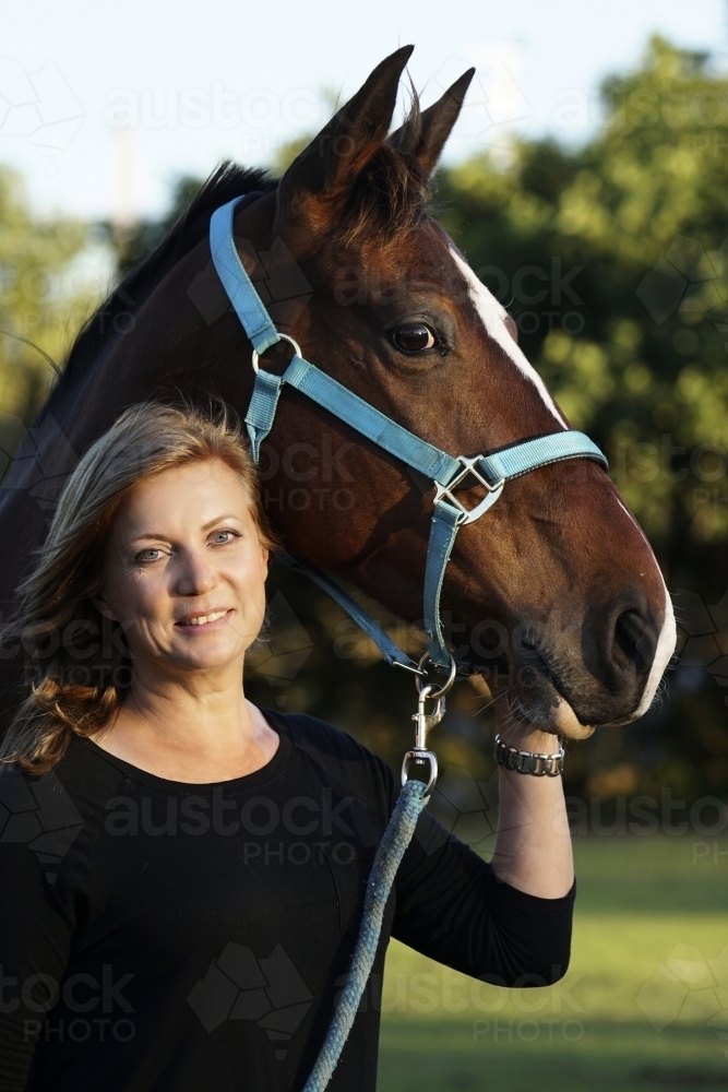 Close up of woman smiling next to horse - Australian Stock Image