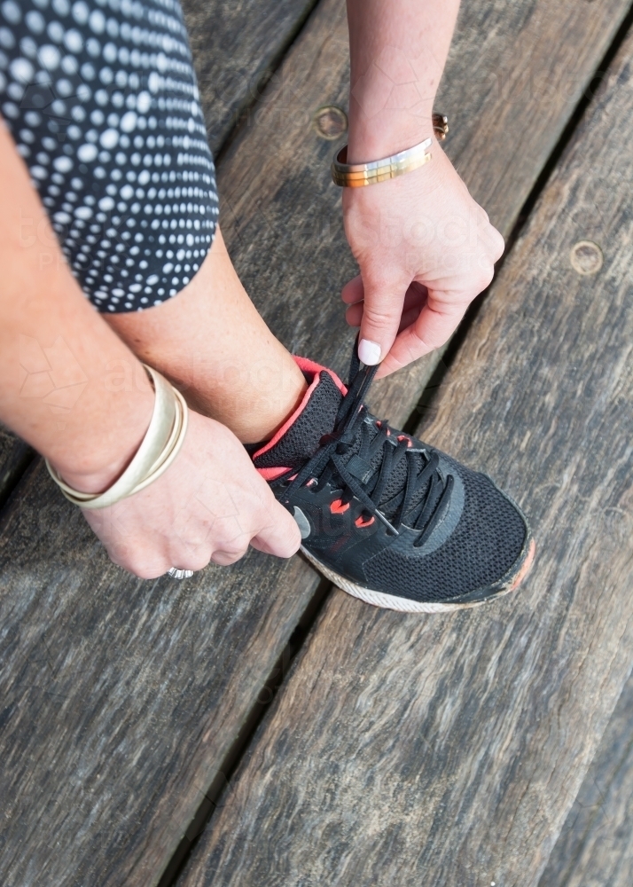 close up of woman tying her shoelace before exercising - Australian Stock Image