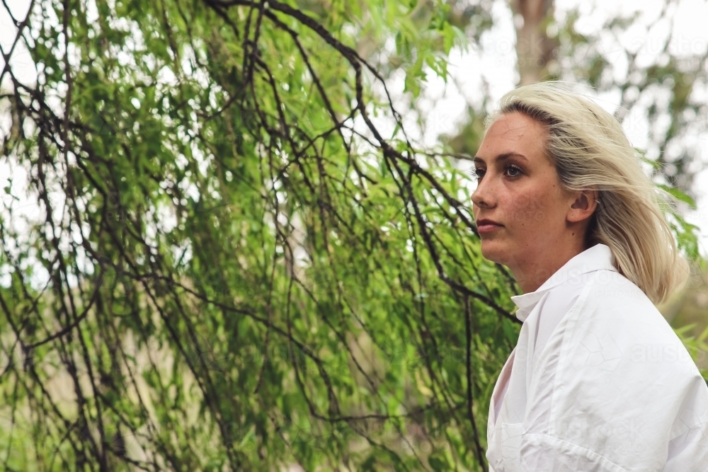 Close up of young blonde woman outside looking away - Australian Stock Image