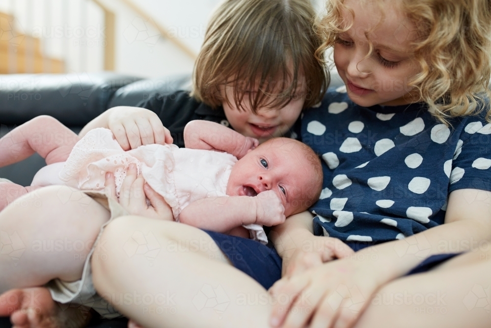 Close up of young boy and girl holding infant - Australian Stock Image