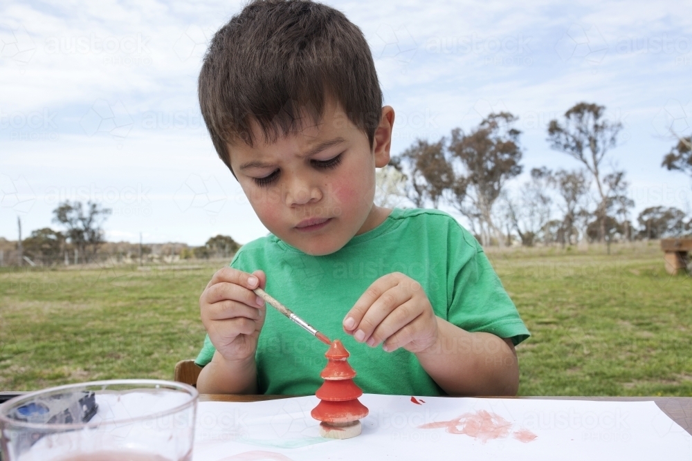 Close up of young boy doing Christmas craft outdoors - Australian Stock Image