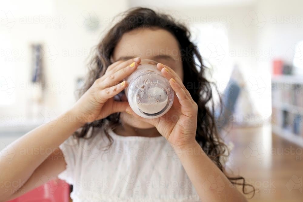 Close up of young girl drinking chocolate milk - Australian Stock Image