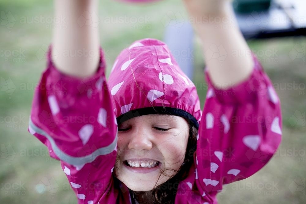 Close up of young girl in pink raincoat - Australian Stock Image