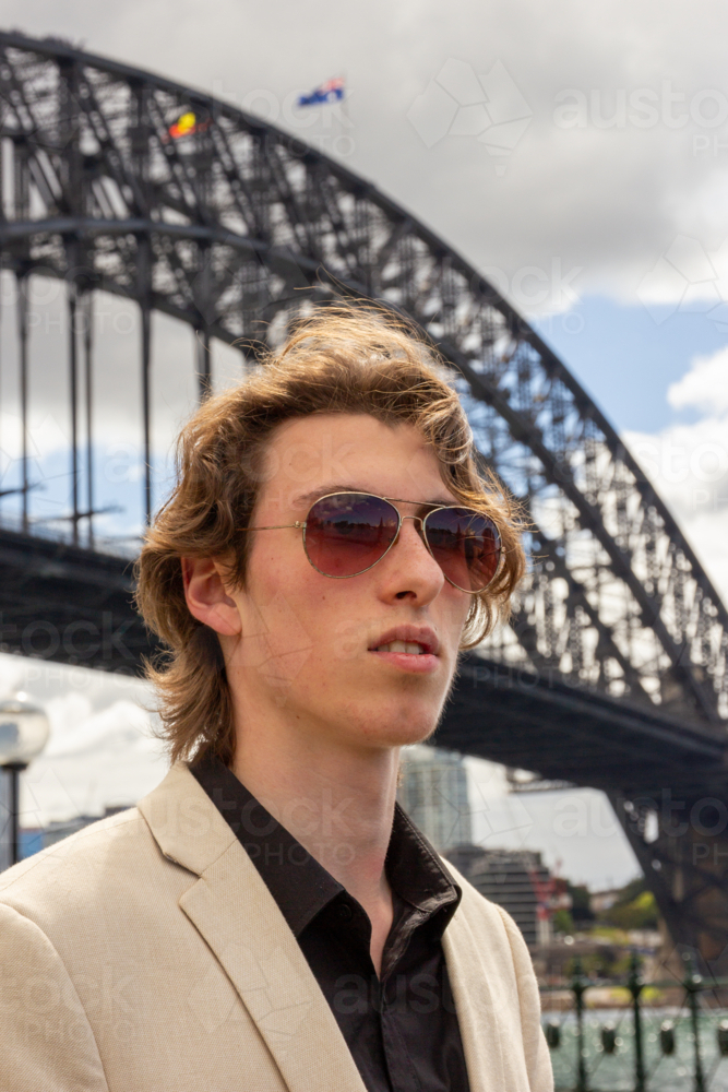 Close up of young man dressed in suit standing with the Sydney Harbour Bridge in the background - Australian Stock Image