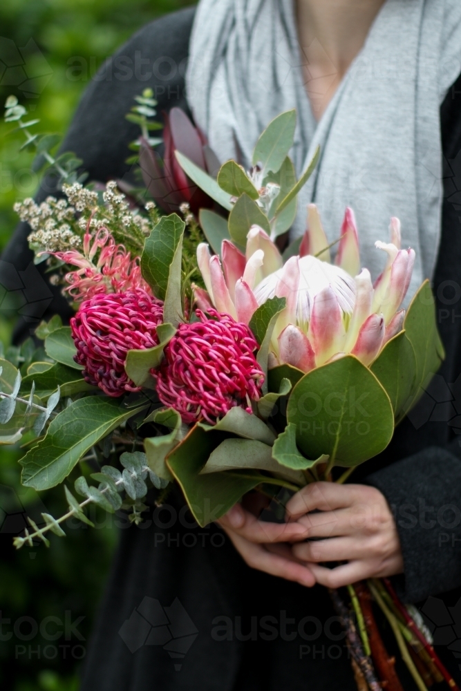 Close up of young woman holding a bouquet of native flowers - Australian Stock Image