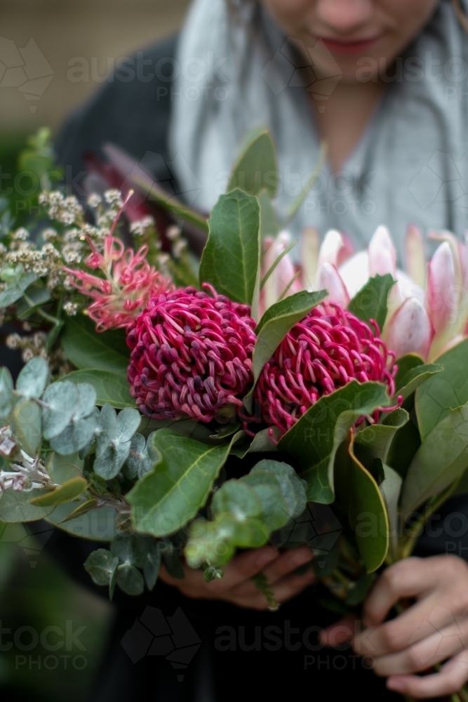 Close up of young woman holding a bouquet of native flowers - Australian Stock Image