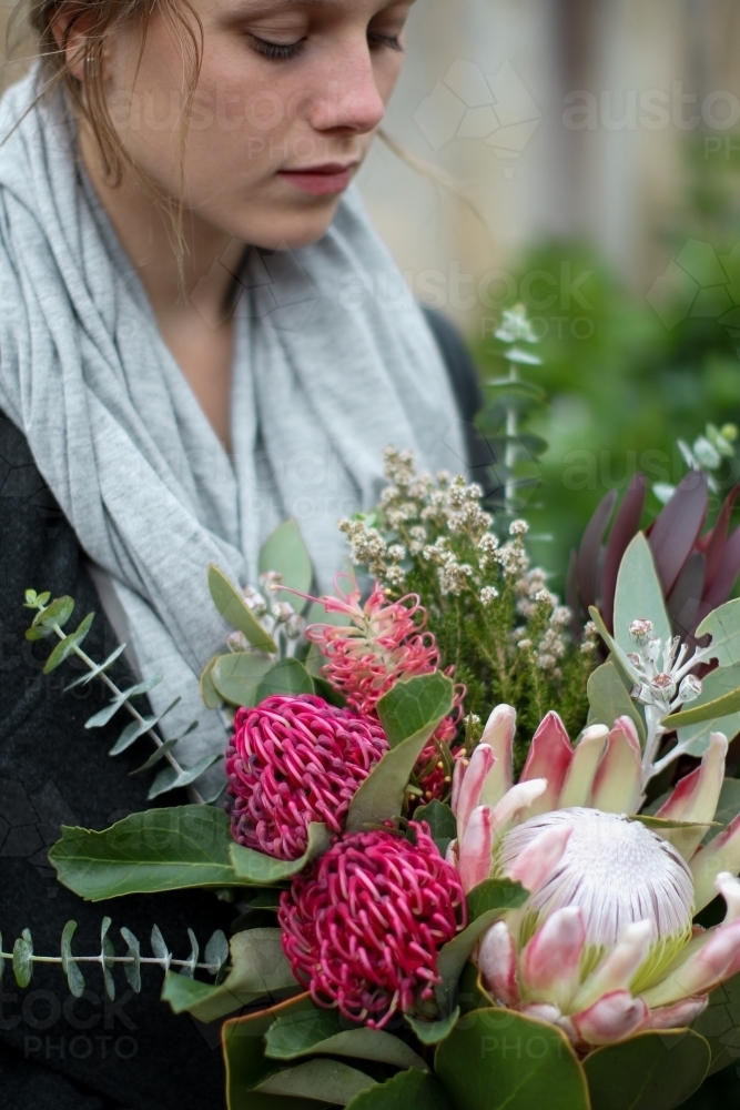 Close up of young woman holding a bouquet of native flowers - Australian Stock Image