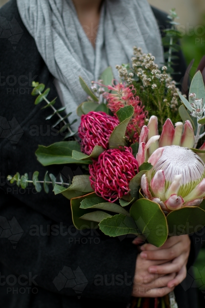 Close up of young woman holding a bouquet of native flowers - Australian Stock Image