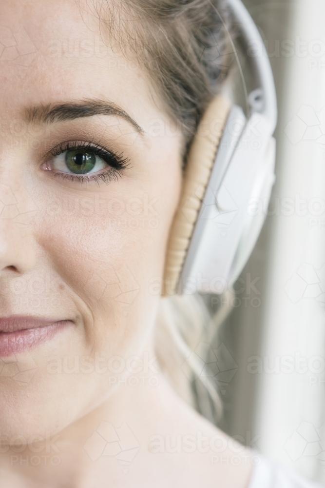 Close up on half a young girl's face and one headphone - Australian Stock Image