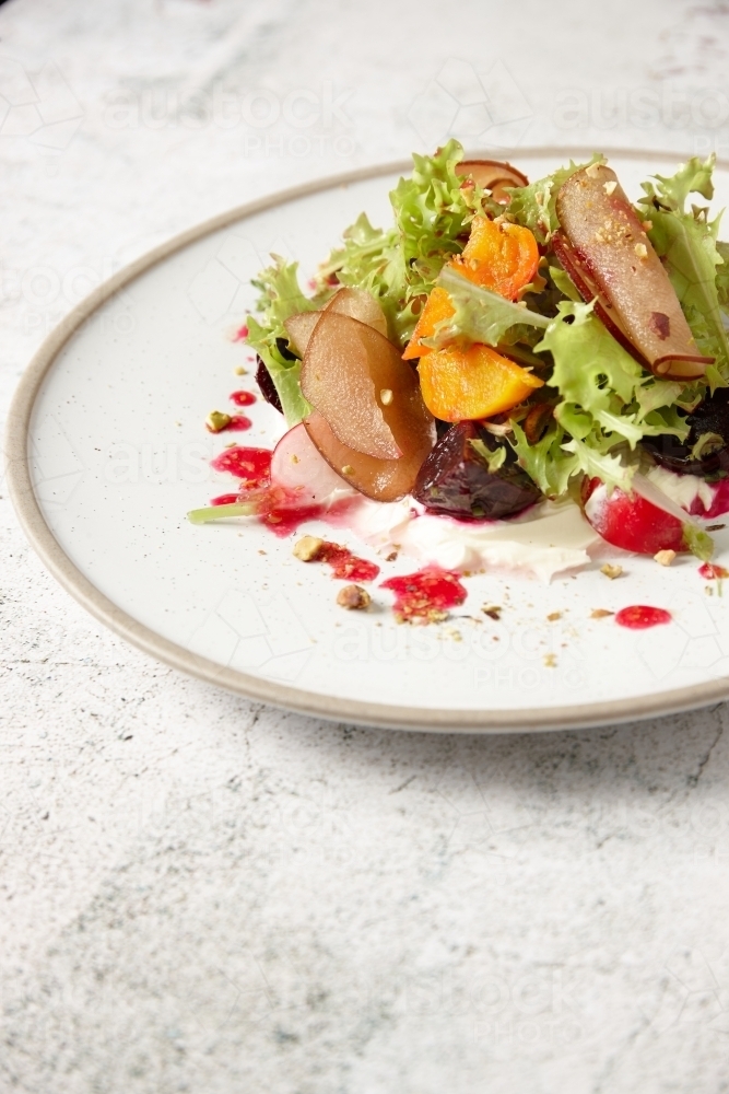 Close up - Plate of fresh salad of lettuce, beetroot, radish, stone fruit and vinaigrette - Australian Stock Image