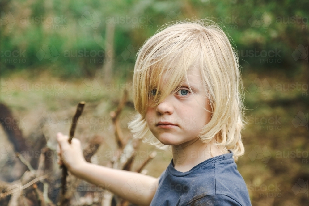 Close up portrait image of young boy with long blond hair covering eyes - Australian Stock Image