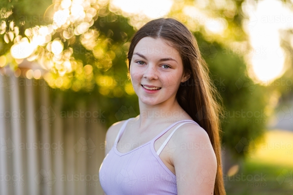 Close up portrait of a fourteen year old brunette girl with bokeh light in the background - Australian Stock Image