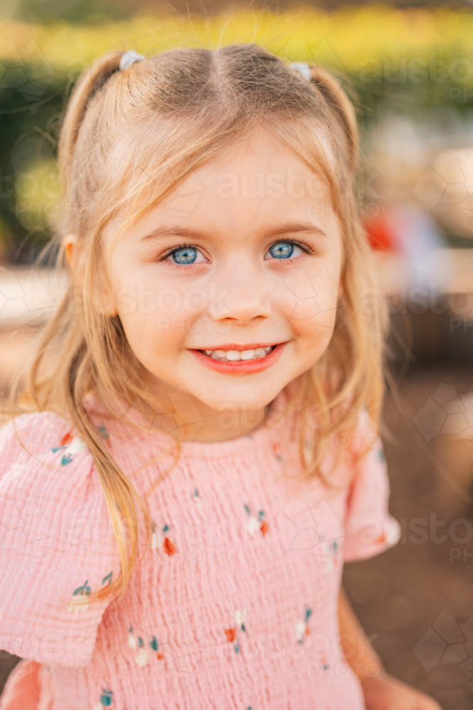 Close up portrait of a smiling preschool age girl with vibrant blue eyes - Australian Stock Image
