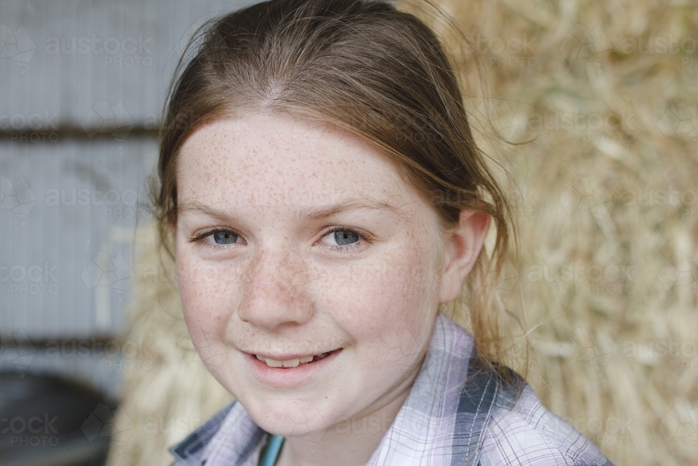 Close up portrait of a young girl in a hay shed - Australian Stock Image