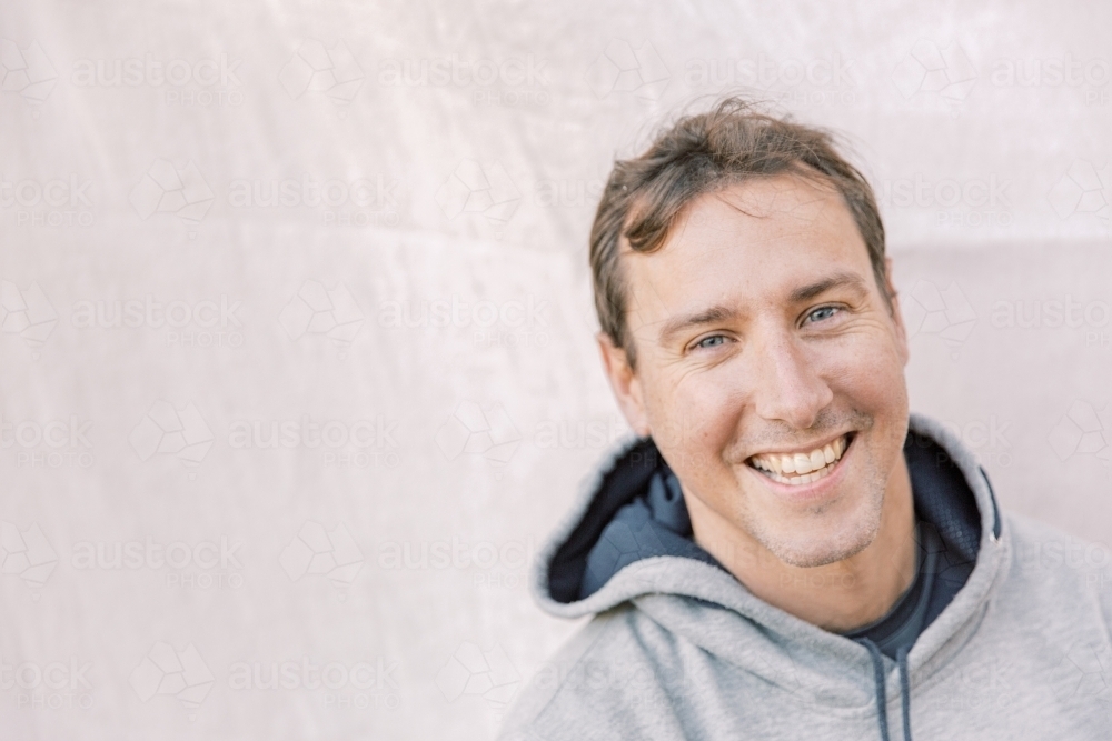 Close-up portrait of a young sportsman smiling and wearing a grey hoodie - Australian Stock Image