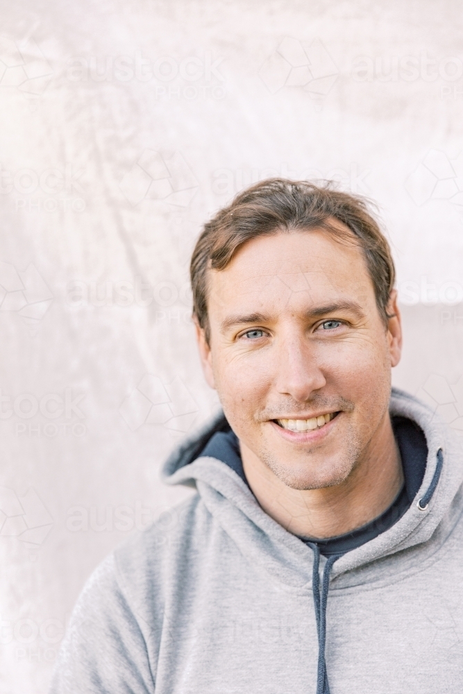 Close-up portrait of a young sportsman smiling wearing a grey hoodie - Australian Stock Image
