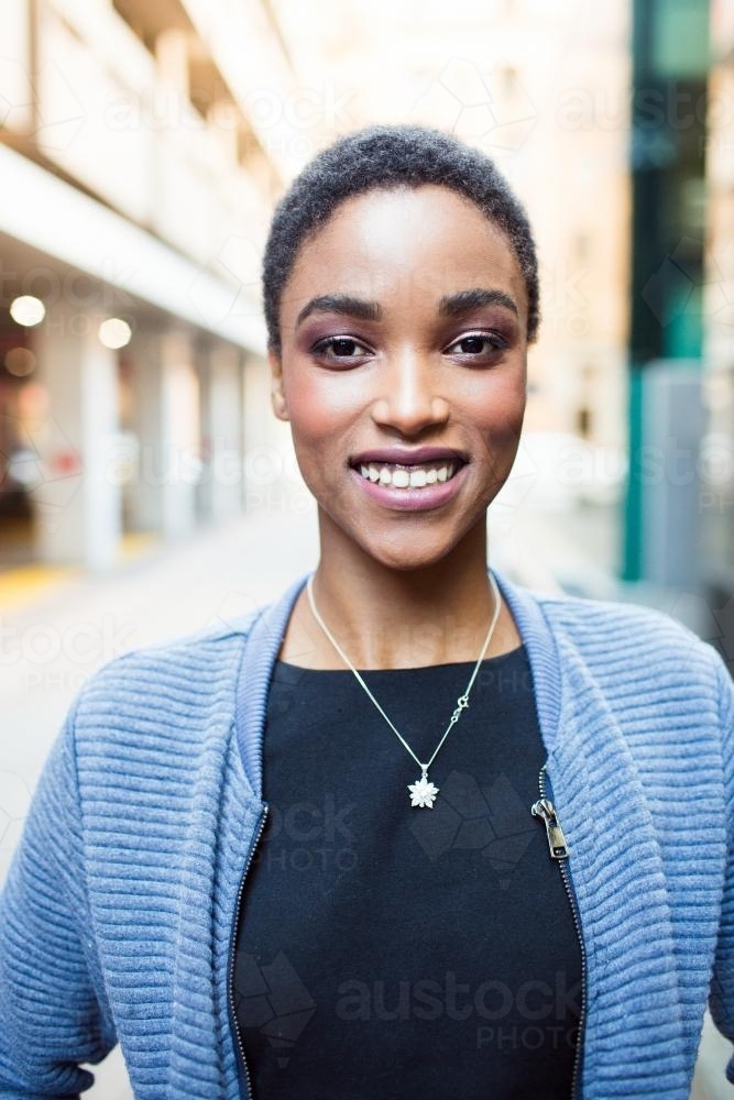 Close up portrait of a young woman smiling in the city - Australian Stock Image